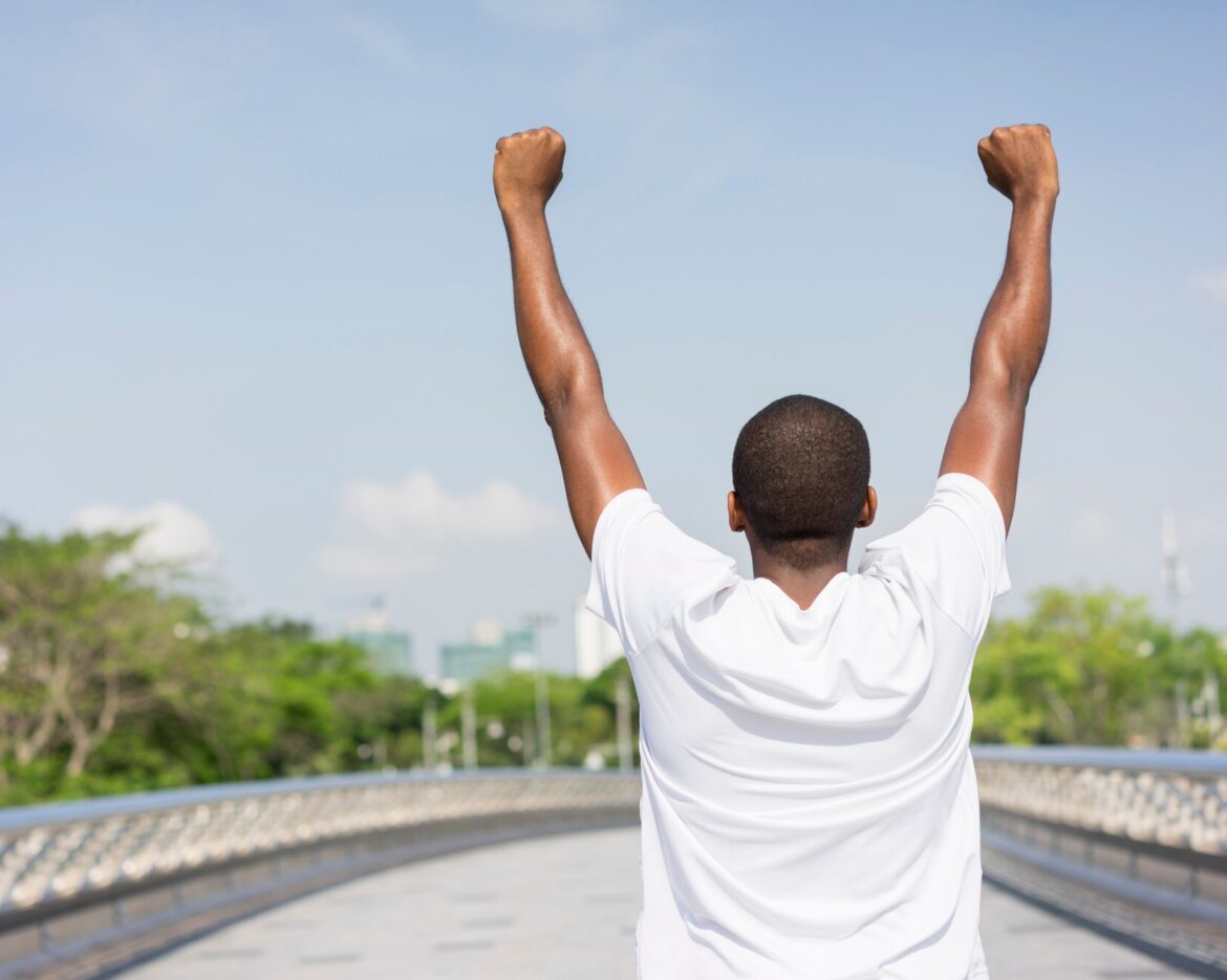 back-black-man-enjoying-city-view-raising-both-hands_1262-12606